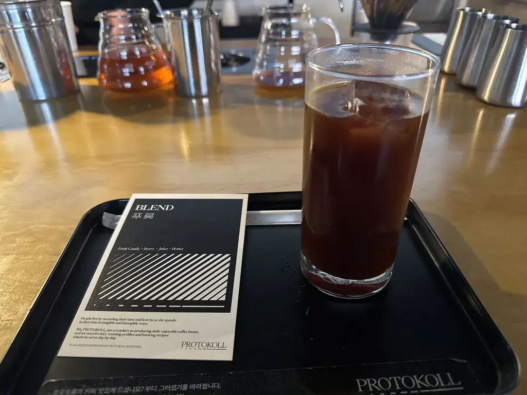 테이블 램프 아래 놓인 아이스 아메리카노와 레몬 케이크